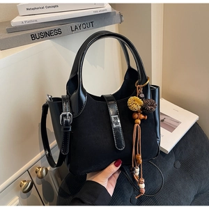 Detail of black matte tote with bohemian pompom charm and silver metal twist lock