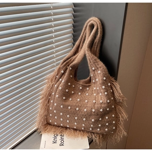 Detail of warm brown knitted tote bag with white pearl accents and fringe tassels