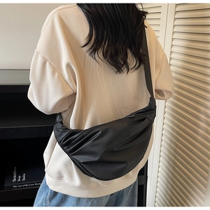 Detail of black crescent crossbody bag showing silky nylon texture and pleated design details