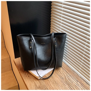 Detail of black wax leather tote bag with gold logo and rivet reinforcement