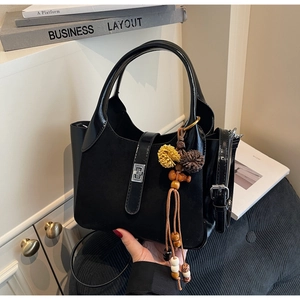 Detail of black bucket bag with suede texture, silver buckle and vintage plush tassel charm