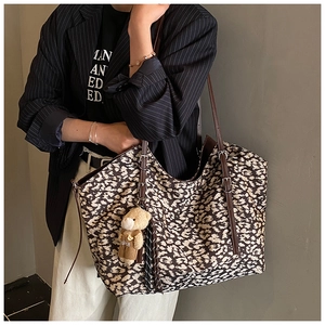 Detail of leopard print tote bag with brown leather strap and cute plush bear charm
