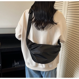 Vue détaillée du sac croissant en nylon noir porté en bandoulière par le mannequin