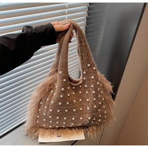 Detail of brown knitted tote bag with white pearls and soft feather fringe accents