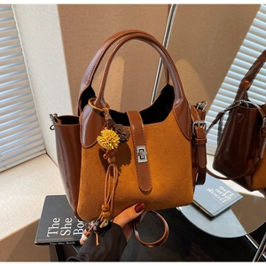 Detail of caramel brown patchwork bucket bag with silver twist lock and tassel charm