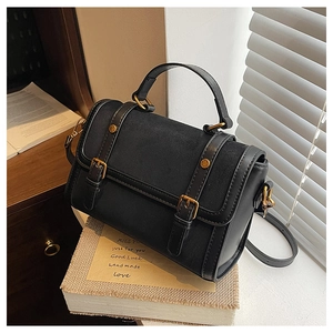 Detail of vintage black crossbody bag with mixed textures and gold buckle hardware
