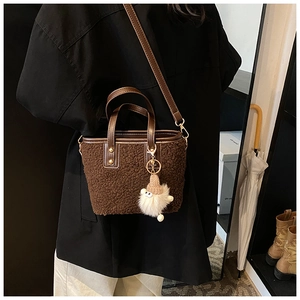 Détail du sac seau en peluche marron foncé avec poignées en cuir et breloque gnome