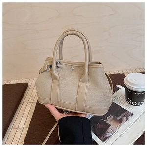 Beige faux suede tote bag with metal buckle on a cozy wooden background and coffee cup