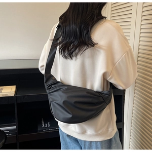 Detail of black crescent crossbody bag showing large capacity and adjustable strap on model