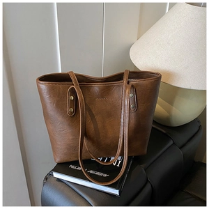 Close-up of vintage dark brown tote bag with leather texture and rivet handle detail