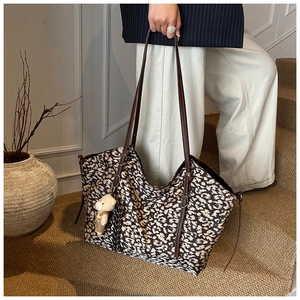 Detail of large leopard print suede tote bag with brown straps and cute bear charm