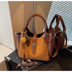 Detail of vintage orange suede bucket bag with brown leather trim and tassel charm