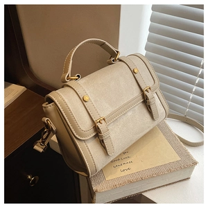 Detail of retro beige canvas crossbody bag with faux leather trim and gold studs
