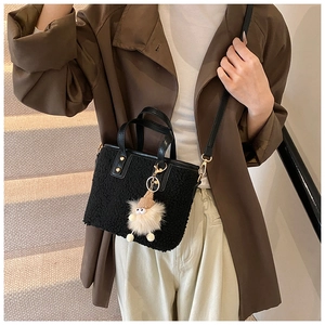 Détail du sac seau en polaire noire avec anses en cuir et breloque en peluche mignonne