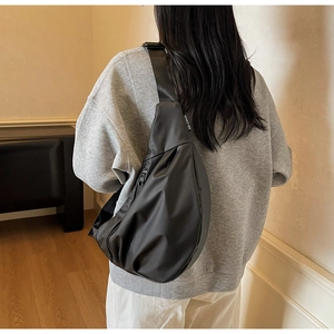 Detailed back view of a black minimalist nylon dumpling bag worn as a crossbody