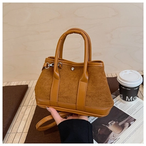 Detail of vintage brown suede handbag showing stitching and adjustable shoulder strap