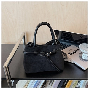 Detail of a chic black matte handbag with belt buckle decor in an office setting