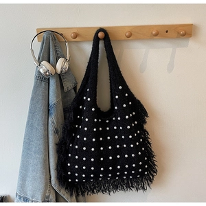 Detail of black faux fur tote bag with white pearl accents and long fringe tassels