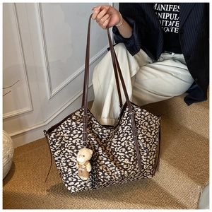 Detail of vintage leopard print tote bag with brown leather handles and bear charm accessory