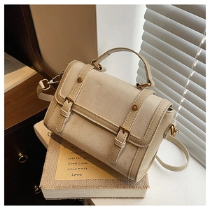 Detail of vintage beige flap bag with contrast paneling and dual buckle straps