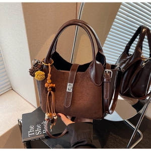 Detail of dark brown matte suede handbag with bohemian tassel and silver metal twist lock