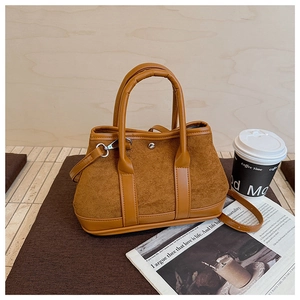 Detail of tan faux suede bucket bag featuring metallic button and adjustable strap