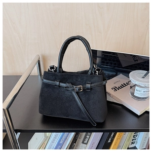 Close-up of matte black bucket bag with smooth leather handles on a modern shelf decor