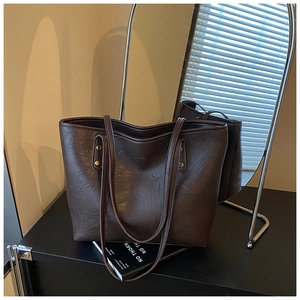 Detail of coffee brown tote bag with pleated leather texture and metallic rivet accents