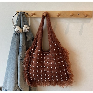 Close-up of brown knitted tote bag with white pearl beads and stylish fringe texture