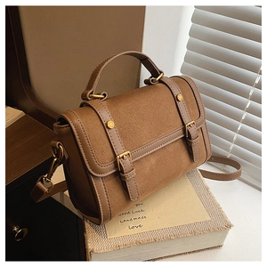 Detail of vintage brown shoulder bag showing suede and leather patchwork with gold hardware