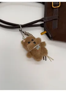 Dettaglio del ciondolo a forma di cane in peluche con collana di perle su borsa marrone