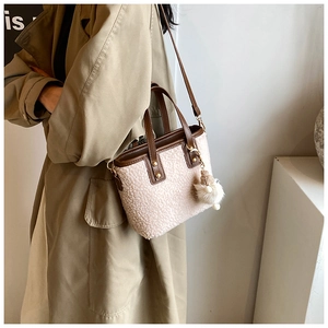 Chic sac seau en peluche beige avec bordure marron porté par un mannequin en trench d'automne