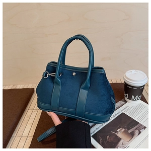 Detail of dark blue velvet bucket bag featuring leather handles and silver metal hooks