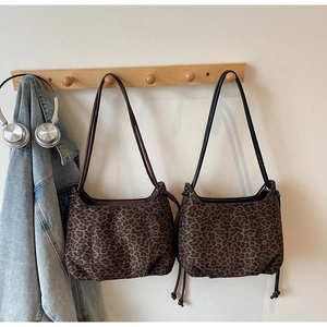 Detail view of leopard print tote bags in brown and black styles on a wooden rack