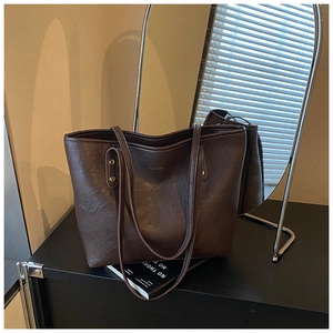 Detail of dark brown tote bag with vintage leather texture and gold rivet hardware