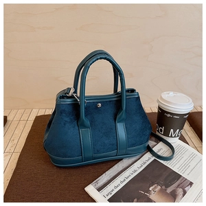 Detail view of the blue suede bucket bag texture with silver stud hardware accents