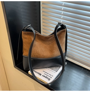 Detail of minimalist tote bag with brown suede upper and black smooth leather bottom finish