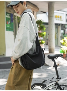 Dettaglio della borsa a mezzaluna in nylon nero con coulisse laterale e tracolla larga
