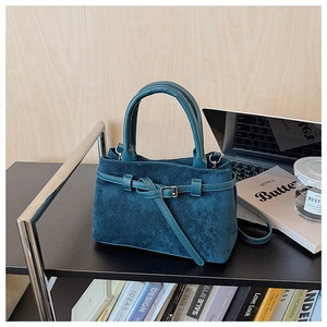 Detailed view of dark cyan suede handbag with a top handle and buckle decoration