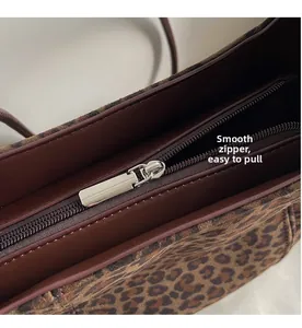 Macro shot of the smooth silver metal zipper and brown lining of leopard tote bag
