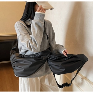 Detail of black large capacity nylon crossbody bag featuring stylish pleated crescent design