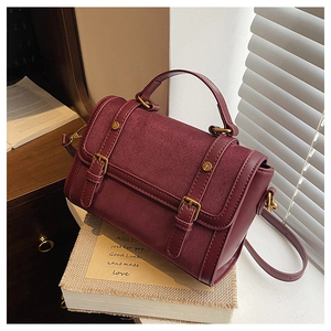 Detailed macro view of vintage burgundy handbag showing suede texture and metal buckle