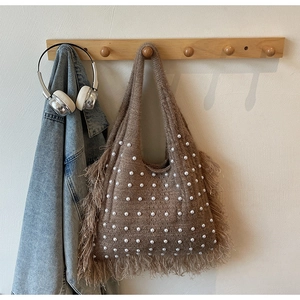 Detail of brown knitted tote bag featuring white faux pearls and vintage fringe trim