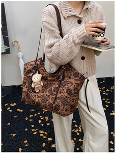 Detail of vintage brown paisley tote bag with plush bear charm on a shoulder strap