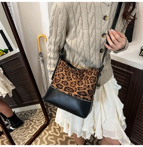 Detail of leopard print suede crossbody bag worn by a model in a cozy indoor setting