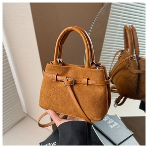 Close-up of caramel suede crossbody bucket bag with smooth leather handle and metal buckle