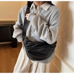 Detail of black pleated crescent crossbody bag showing soft nylon fabric and wide strap