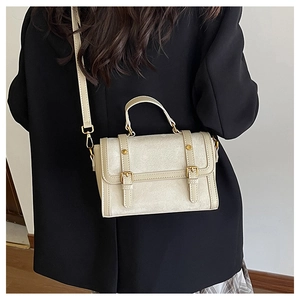 Detail of beige vintage crossbody bag showing gold metal buckles and textured leather