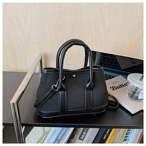 Detail of black faux suede bucket bag with leather accents and silver metal buckle closure