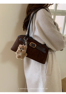 Dettaglio borsa a guscio vintage marrone opaco con cinturini in pelle e ciondolo cane
